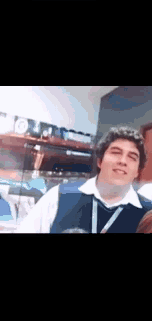 a man in a white shirt and blue vest is smiling for the camera