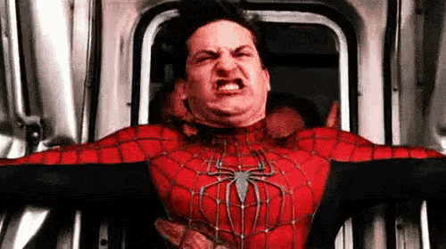 a man in a spiderman costume is making a funny face while standing in a doorway .