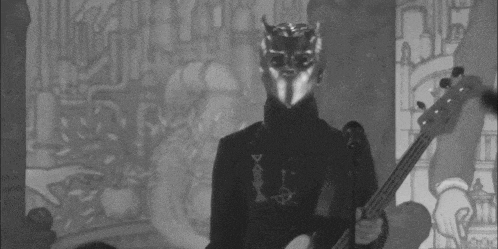 a black and white photo of a man in a mask playing a guitar .