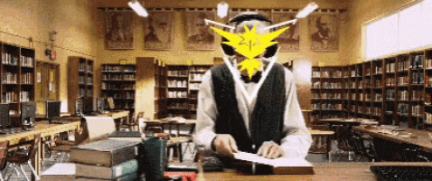 a man sitting at a desk in a library with a yellow light shining on his face