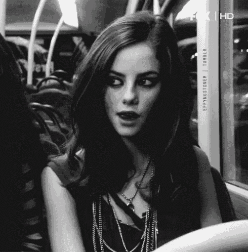 a woman is sitting on a bus with a necklace around her neck .