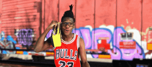 a man wearing a bulls jersey is holding a yellow object
