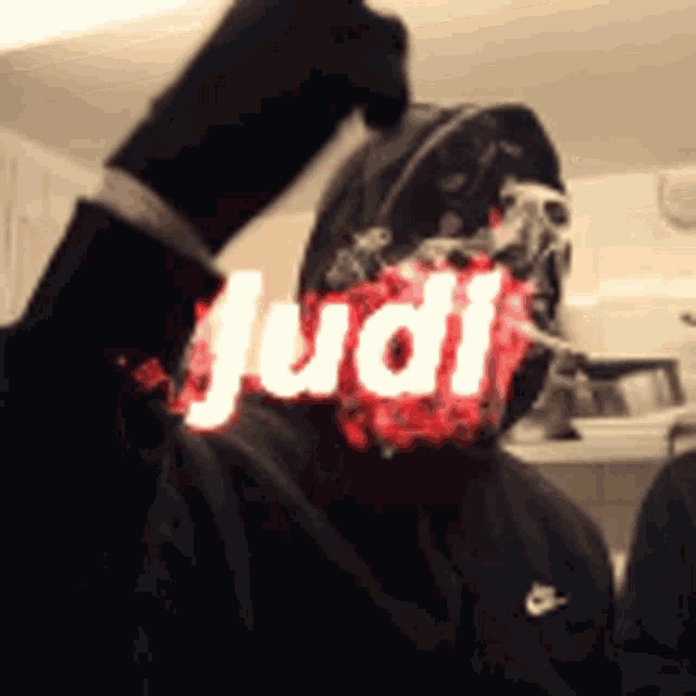 a man wearing a black jacket with the word judi written on his face