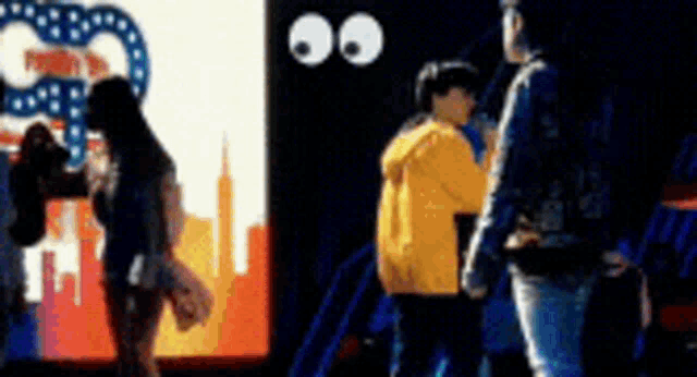 a blurry photo of people standing in front of a screen with googly eyes