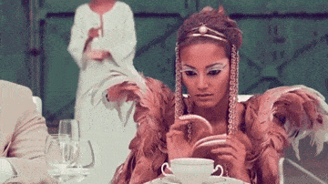 a woman with long nails sits at a table with a cup of coffee