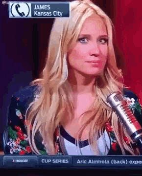 a woman is sitting in front of a microphone with james kansas city written on the screen behind her
