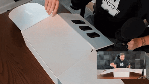 a man wearing a shirt that says ' stealth ' on it is opening a white box