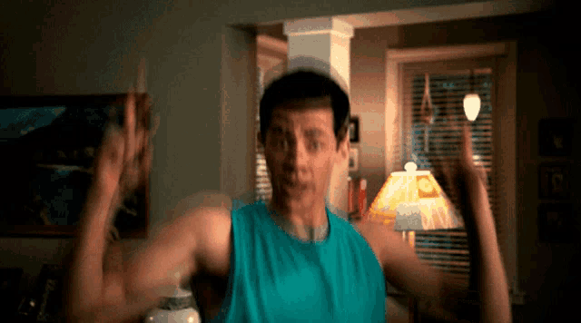 a man in a blue tank top is flexing his muscles