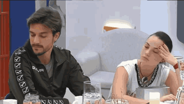 a man and a woman are sitting at a table with glasses of water