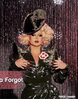 a picture of a drag queen with a forgot sign behind her