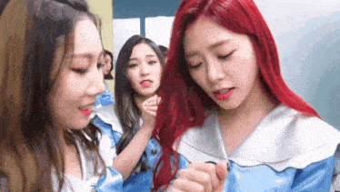 a girl with red hair is standing next to two other girls