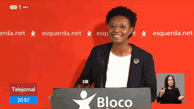 a woman stands behind a podium with the word bloco on it