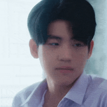 a close up of a young man 's face with a white shirt on .