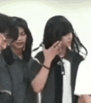a group of people are standing next to each other and one of them is covering her face .