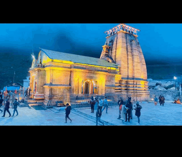 a group of people are standing in front of a temple lit up at night .