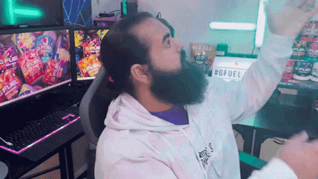 a man with a beard is sitting in front of a computer with a sign that says #gffuel on it