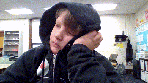 a person wearing a black hoodie with a red circle on the front