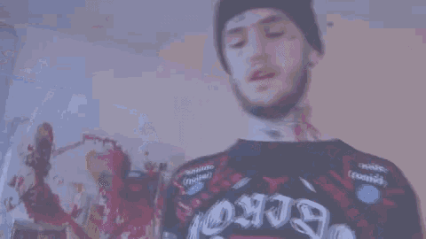 a man wearing a beanie and a sweater is standing in a room holding a skateboard .