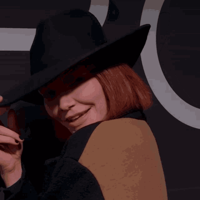 a woman wearing a black hat and a brown jacket