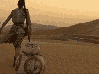 a person is walking with a bb-8 robot in the desert .