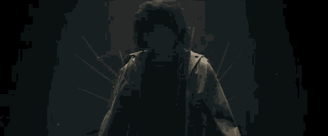 a person in a hooded jacket is standing in a dark room