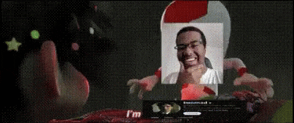 a man with glasses and a santa hat is smiling in front of a computer screen .
