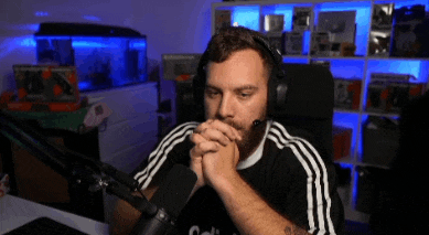 a man wearing headphones is sitting in front of a microphone with his hands folded