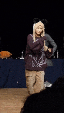 a woman wearing a sweater that says ' a ' on it is dancing on a stage