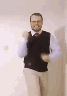 a man wearing a vest and tie is dancing in a room