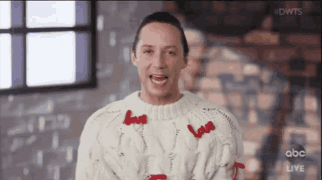 a man wearing a white sweater with red hearts on it is on abc live