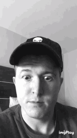 a man wearing a hat with a skull on it looks at the camera