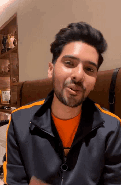 a man with a beard is wearing an orange shirt and a blue jacket