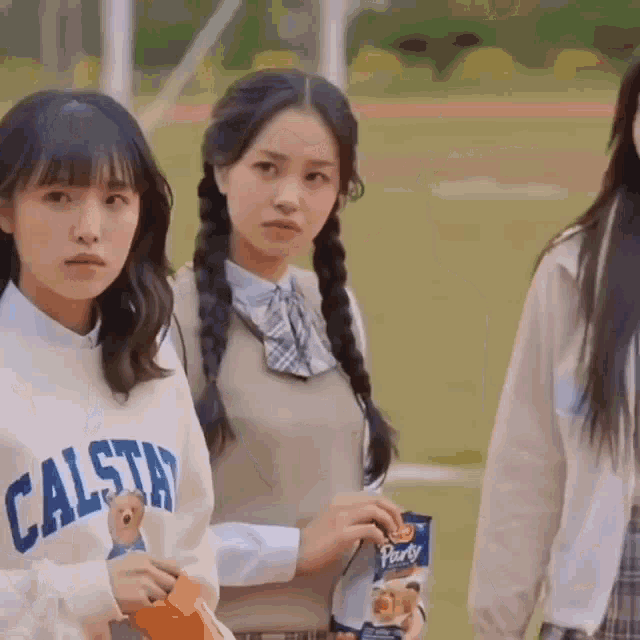 a girl wearing a calstar sweatshirt is holding a bag of party crackers .