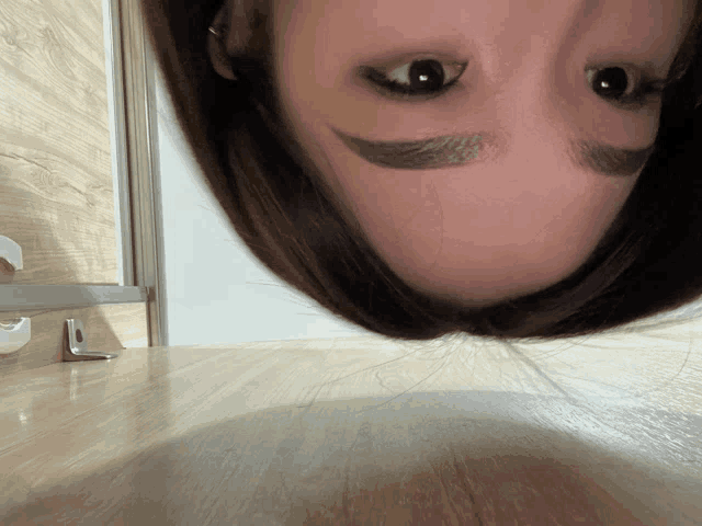 a close up of a woman 's face with a reflection of the letter l on the floor