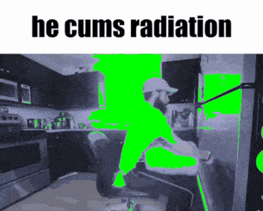a man sitting in a chair in a kitchen with the words he cums radiation