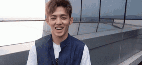 a young man is standing on top of a building and smiling .
