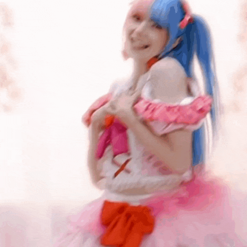 a woman in a pink dress with blue hair and a red bow is smiling .