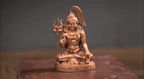 a bronze statue of shiva is sitting on a wooden table
