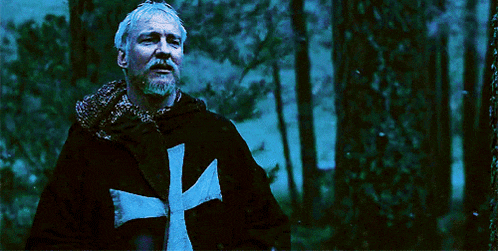 a man in a black robe with a white cross on his chest
