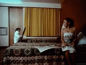 a man and a woman are sitting on a bed in a hotel room