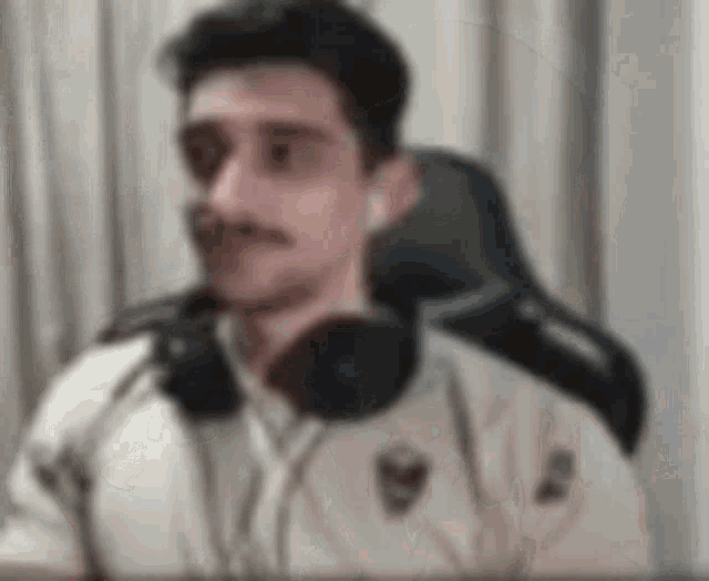 a man with a mustache is wearing headphones and a jacket .