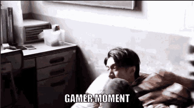 a man is laying on a bed with the words gamer moment written above him