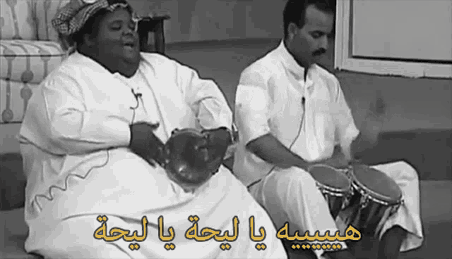 a black and white photo of two men playing drums with arabic writing on it