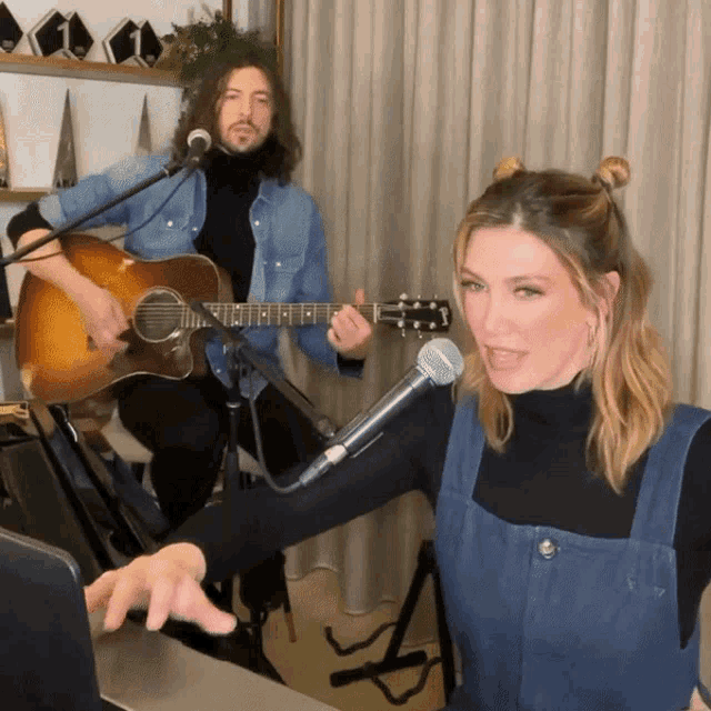 a man is playing a guitar and a woman is singing into a microphone
