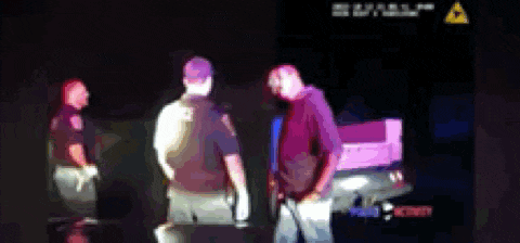 a blurred image of a man talking to a police officer in a dark room