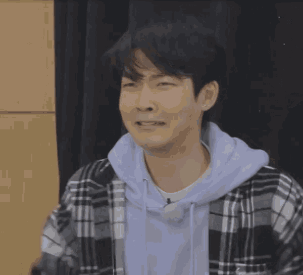 a young man in a plaid shirt is making a face