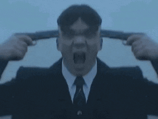 a man in a suit is holding a gun to his ear