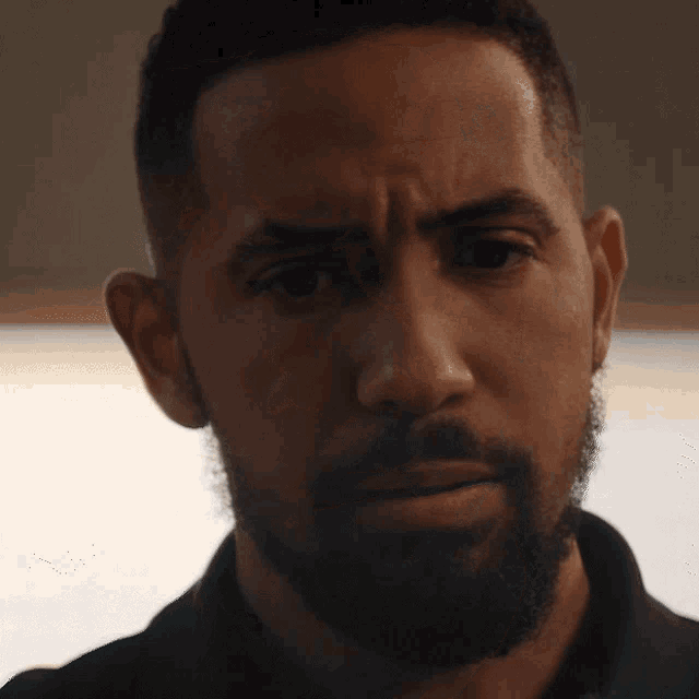 a man with a beard is looking at the camera with a serious look on his face