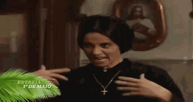 a woman wearing a black hat and a cross necklace is making a funny face in front of a picture of jesus .