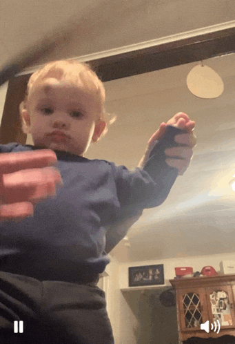 a little boy in a blue shirt is being held by a person in a living room